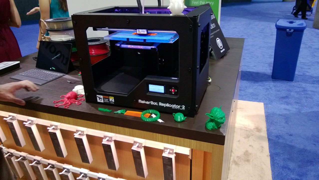 A MakerBot Replicator 2 printer on display alongside sample prints