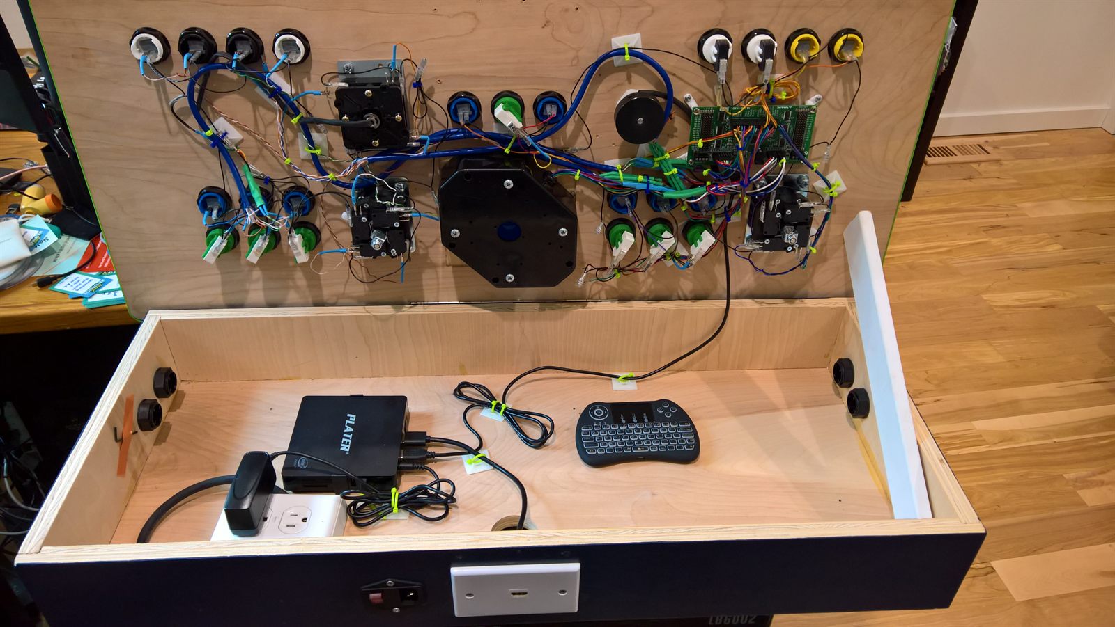 Cabinet open with tidied wiring and a wireless keyboard inside the bay