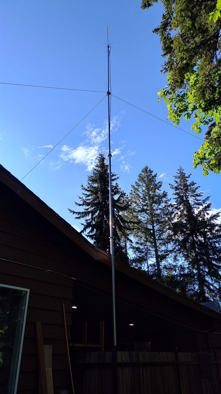 Comet GP-6 vertical antenna on a 33-foot telescoping mast against a blue sky next to an A-frame house