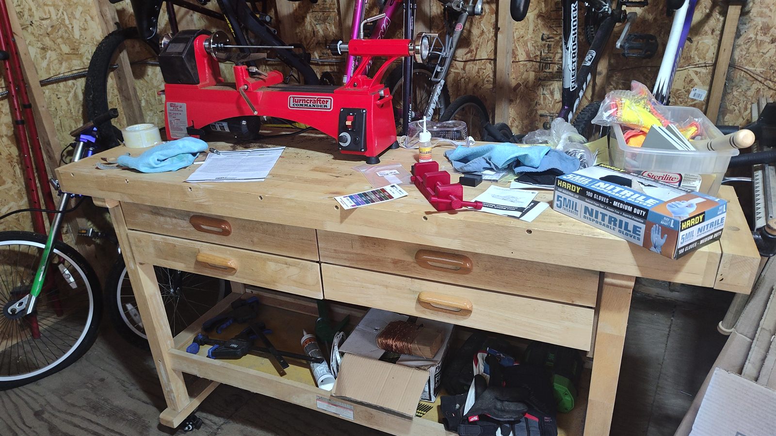 The wheeled hardwood workbench with the lathe mounted on top, drawers and storage shelf visible